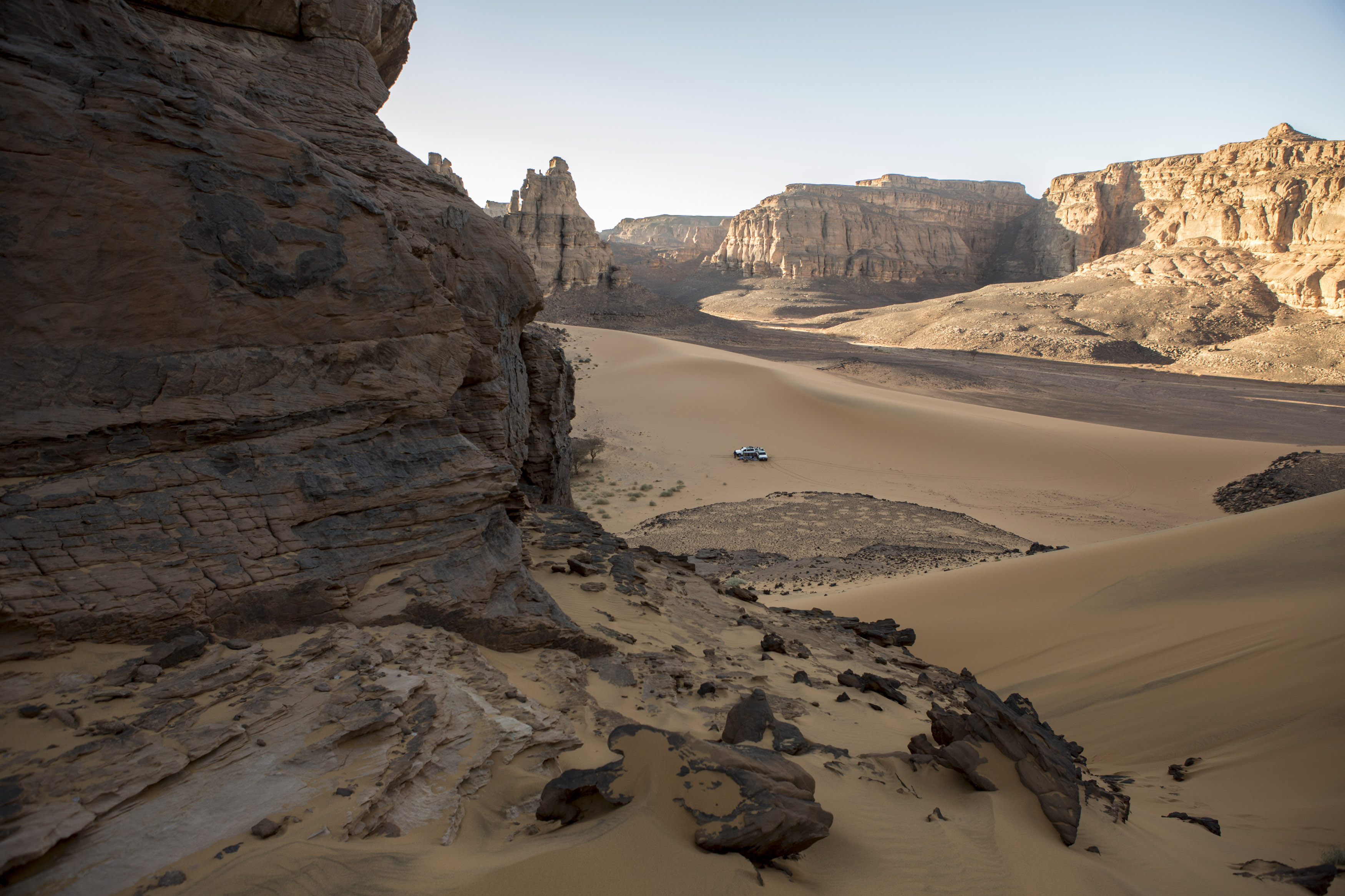 Two crews with their 4x4 vehicles are preparing for the evening bivouac in the Tadrart. La Tadrart (200 km southeast)
The Tadrart (200 km southeast of Djanet) is located in the south of the Tassili N'Ajjer National Park and is part of one of the most beautiful desert in the world but above all the central Sahara.
From huge canyons to cliffs carved with rocky peaks of various shapes mix with dunes of colored sand with yellow and red reflections. The Tadrart, Algeria-February 5, 2017. 
Deux équipages avec leur véhicules 4x4 se préparent pour le bivouac du soir dans la Tadrart. La Tadrart (200 km au sud-est de Djanet) se situe dans le sud du Parc National du Tassili N'Ajjer et il fait partie d’un des plus beau désert au monde mais avant tout du Sahara central. 
D’immenses canyons aux falaises sculptées avec de pitons rocheux aux formes les plus diverses  se mélangent avec des dunes de sable coloré aux reflets jaune et rouge. La Tadrart,, Algérie-5 février 2017.